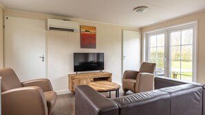 A living room with a TV, sofa, chairs, and a wooden coffee table. - Amazing home in Wagenborgen with WiFi (Wagenborgen)