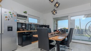 A modern kitchen with a dining area, featuring a built-in oven, a water dispenser, and a coffee machine. - Pet friendly home in Vir (Vir)