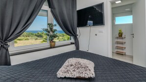 A bedroom with a bed, a TV mounted on the wall, a window with curtains, and a view of the outdoors. - Pet friendly home in Vir (Vir)