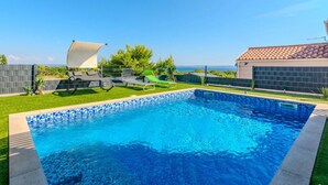 A swimming pool with a tiled edge, surrounded by a grassy area with lounge chairs and a white canopy. - Pet friendly home in Vir (Vir)