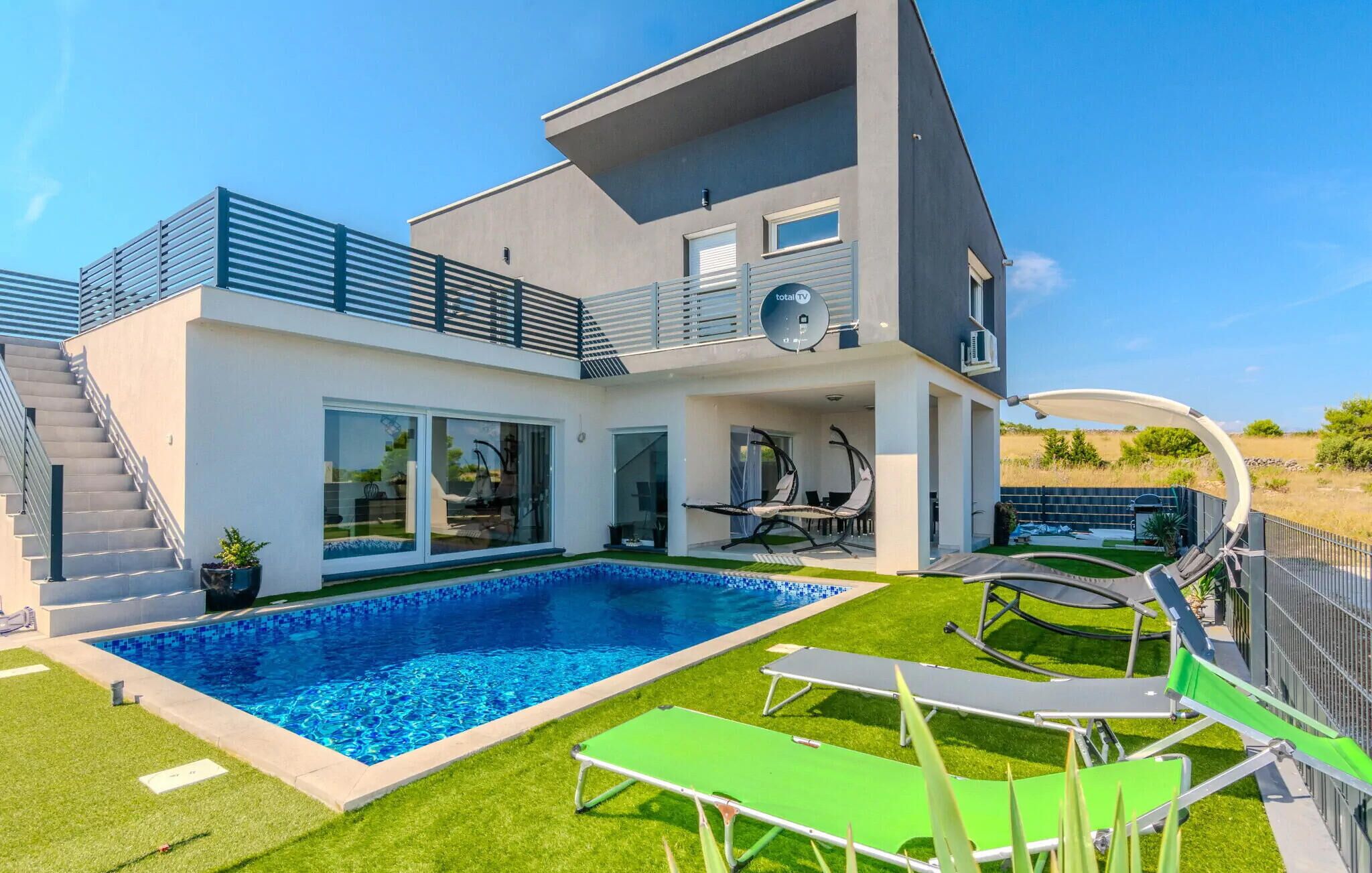 Une maison moderne à deux étages dotée d’une piscine, d’un espace salon extérieur et d’un patio couvert.