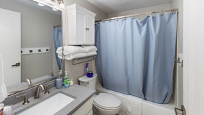 A bathroom with a sink, mirror, toilet, and shower curtain. - Cozy home in Logan, close to USU (Logan)