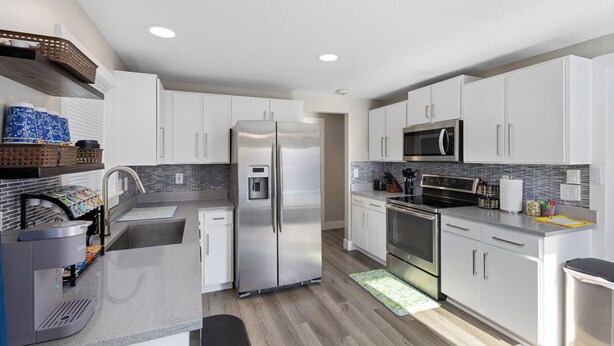 A modern kitchen with white cabinets, stainless steel appliances, and a grey countertop. - Cozy home in Logan, close to USU (Logan)