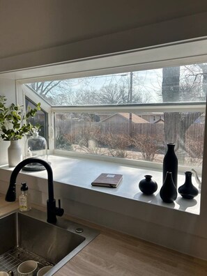 A kitchen with a window, a sink, and a vase on the windowsill.