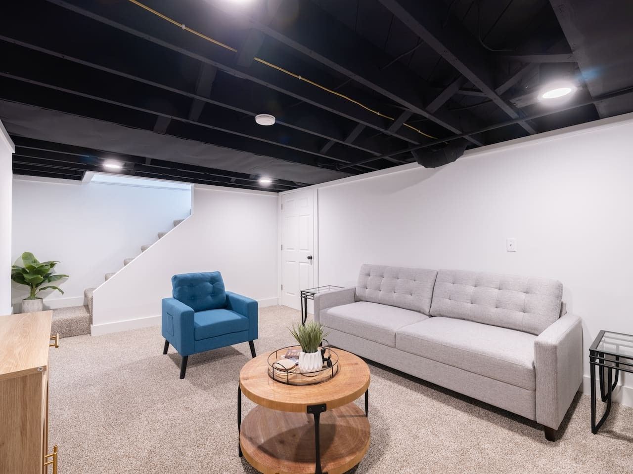 A modern living room with a grey sofa, a blue armchair, and a wooden coffee table.