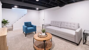 Un interior moderno con un sofá gris, un sillón azul y una mesa de centro de madera.