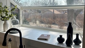 Una cocina con ventana, un lavamanos y un florero en el alféizar.