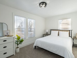 A bedroom with a bed, bedside tables, a dresser, and a potted plant.