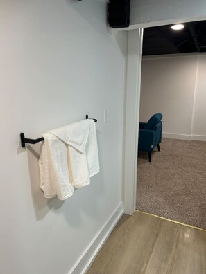 A room with a white wall, a black towel rack, a blue chair, and a carpeted floor.