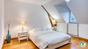 Een slaapkamer met een bed, nachtkastjes, een lamp, een vaas en een raam.