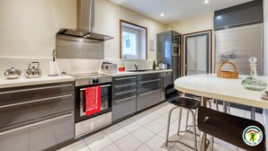 Een moderne keuken met roestvrijstalen apparatuur, een ingebouwde oven en een eethoek met een tafel en stoelen.