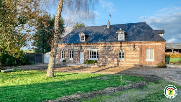 Een tweelaags bakstenen huis met een schuin dak, schoorsteen en een klein portaal met plantenpotten.