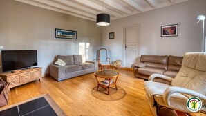 Een ruime woonkamer met een grote flatscreen-tv, twee banken, een salontafel en een houten kast.