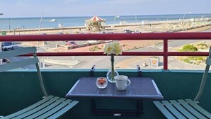A balcony with a table, two chairs, and a view of the beach and ocean. - Gîtes de France® - Au Salon d'Arthur (CRIEL SUR MER)