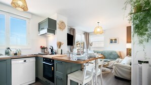 A modern kitchen with a central island, built-in appliances, and a dining area with a sofa and chairs. - Gîtes de France® - Au Salon d'Arthur (CRIEL SUR MER)