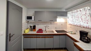 A compact kitchen with grey cabinets, a microwave, a sink, and a coffee maker.