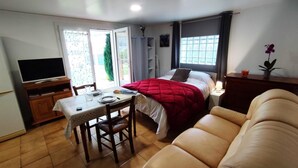 A bedroom with a bed, a TV, a dining table, and a chair.