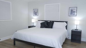 Une chambre à coucher comprenant un lit, deux tables de chevet et deux lampes fixées au mur.