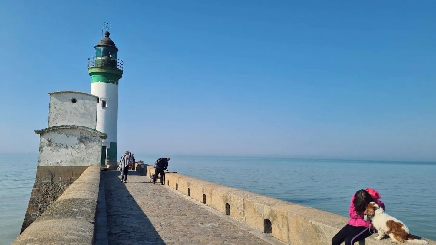 Een vuurtoren aan zee onder een heldere lucht.