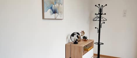 A room with a bed, a wooden nightstand, a globe, a plant, and a black floor lamp.