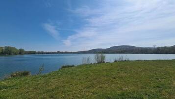 Un lago con rive erbose e colline lontane sotto un cielo sereno.