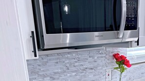 A kitchen with a stainless steel microwave, a black induction cooktop, and a built-in oven. - A Taste Of NOLA (LaPlace)