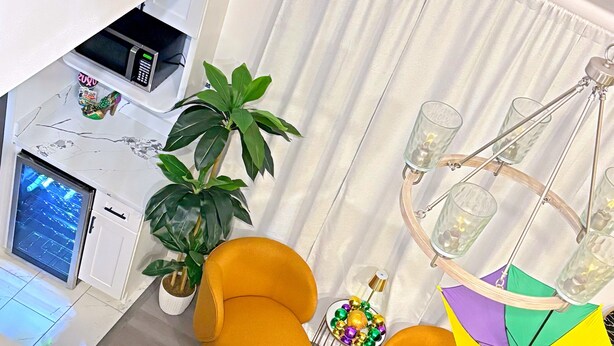 A modern living room with a sofa, a dining table, a potted plant, and a chandelier. - A Taste Of NOLA (LaPlace)