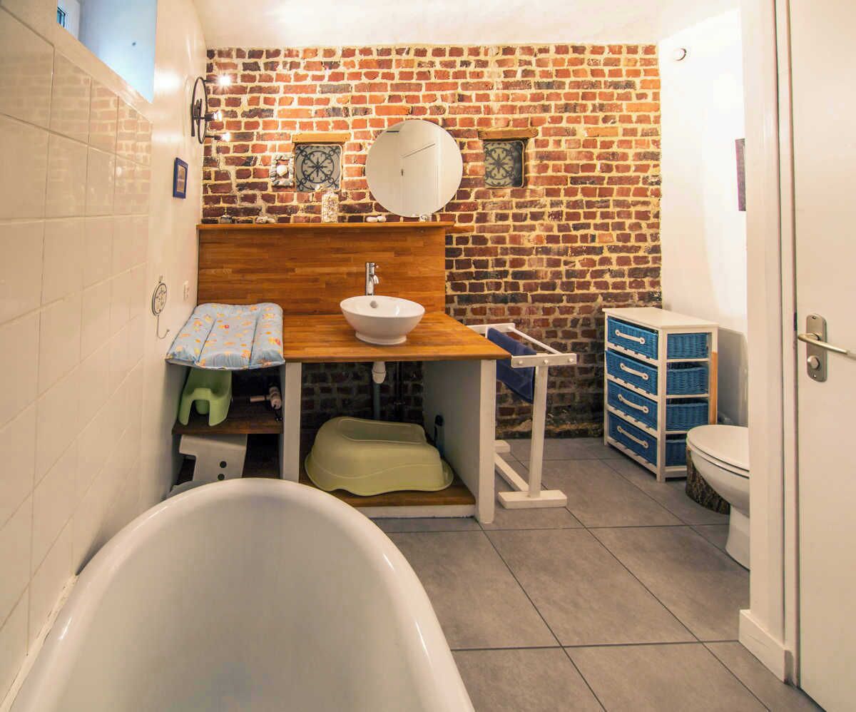 Ein kleines Badezimmer mit Badewanne, einem Holzkosmetikschrank mit Waschbecken und Toilette.