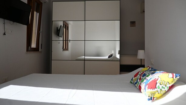 A bedroom with a bed, a wardrobe, a television, and a window. - M417 - Marcelli, comfortable two-room apartment 100 meters from the sea (Marcelli)