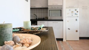 A kitchen with white cabinets, a refrigerator, and a wooden table with decorative items. - M417 - Marcelli, comfortable two-room apartment 100 meters from the sea (Marcelli)