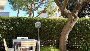 An outdoor seating area with a table and chairs, a spherical light fixture, and a large tree. - M417 - Marcelli, comfortable two-room apartment 100 meters from the sea (Marcelli)