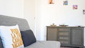 A grey sofa with a cushion that reads 'FUEO LA TU CASA VACANZA,' a small cabinet with drawers, and a tiled floor. - M417 - Marcelli, comfortable two-room apartment 100 meters from the sea (Marcelli)