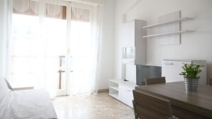 A modern room with a bed, a dining table, a TV, and a plant. - SE141 – Comfortable two-room apartment facing the sea (Senigallia)