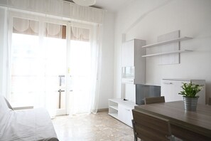 A modern room with a bed, a dining table, a TV, and a plant.