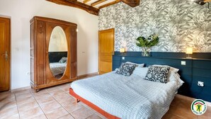 Un dormitorio con cama, armario de madera y papel tapiz floral.