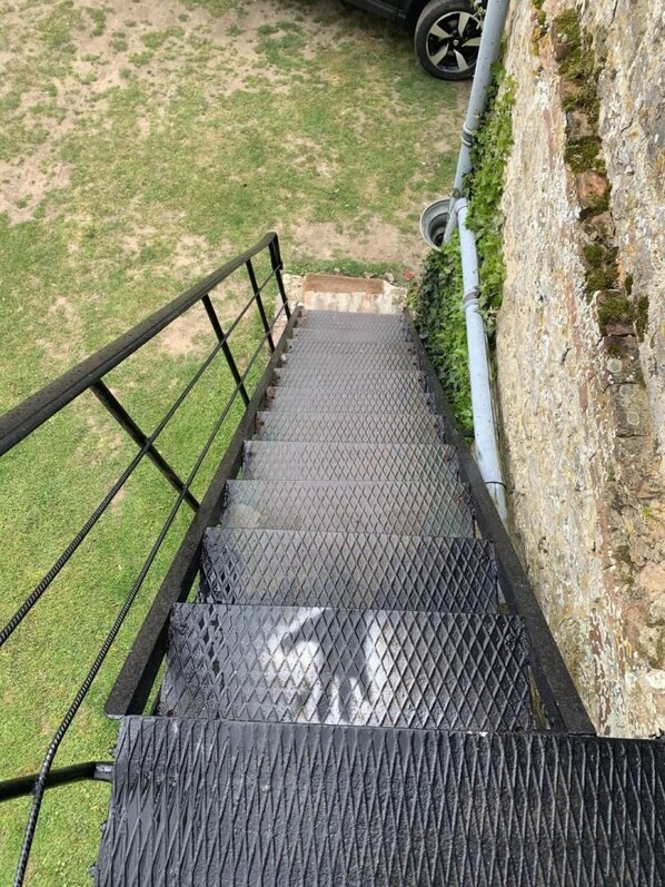 Una escalera metálica con barandilla que lleva a una puerta.