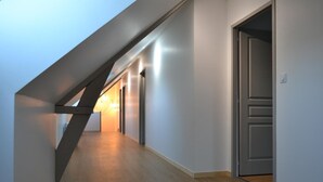 A modern hallway with wooden flooring, a sloped ceiling, and recessed lighting.