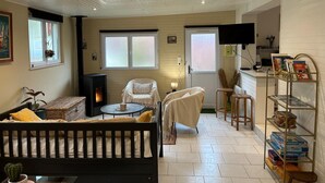 Un salon chaleureux avec une cheminée, un canapé confortable, une petite table ronde et une bibliothèque remplie de livres.