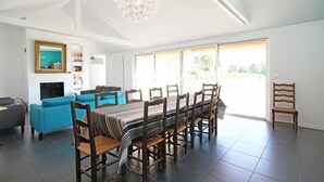 A spacious living room with a dining area, a fireplace, and a large window.