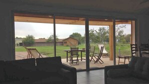 A room with a large sliding glass door leading to an outdoor patio area. Inside, there are two dark-colored sofas and a small table.