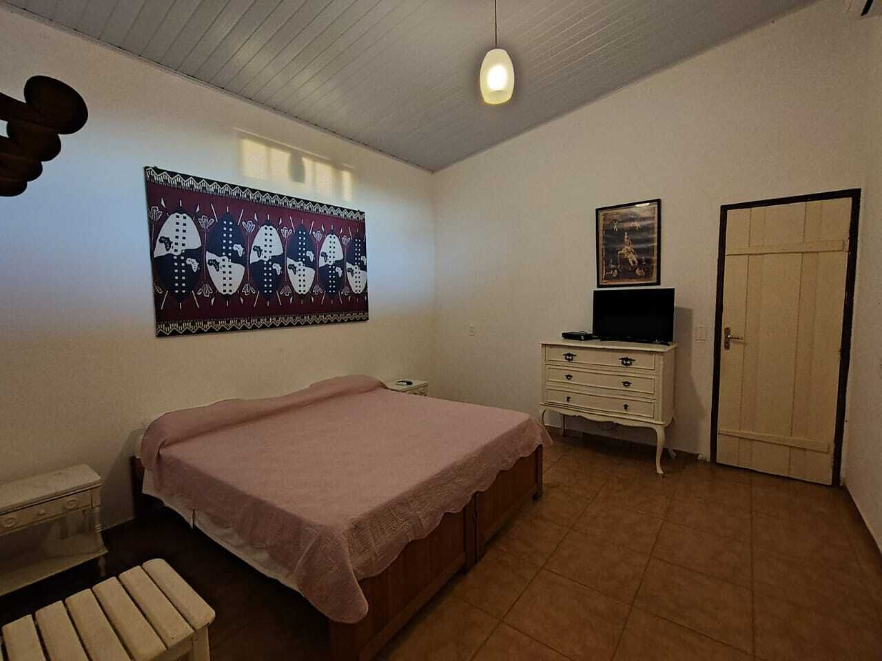 A bedroom with a bed, a dresser, a television, and a door.