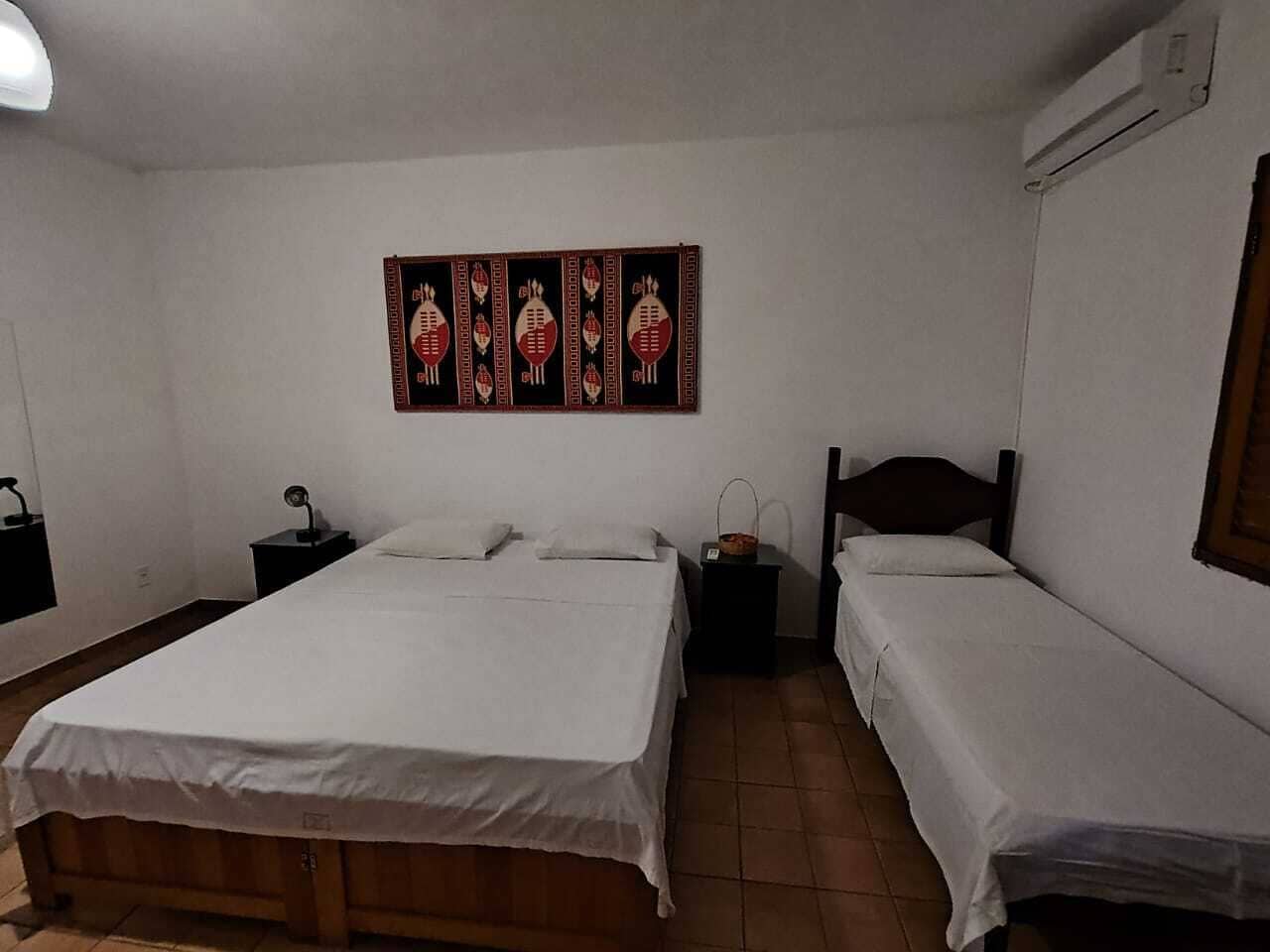 Ein Schlafzimmer mit zwei Einzelbetten, einem Nachttisch mit Lampe und einem an der Wand hängenden Kunstwerk.