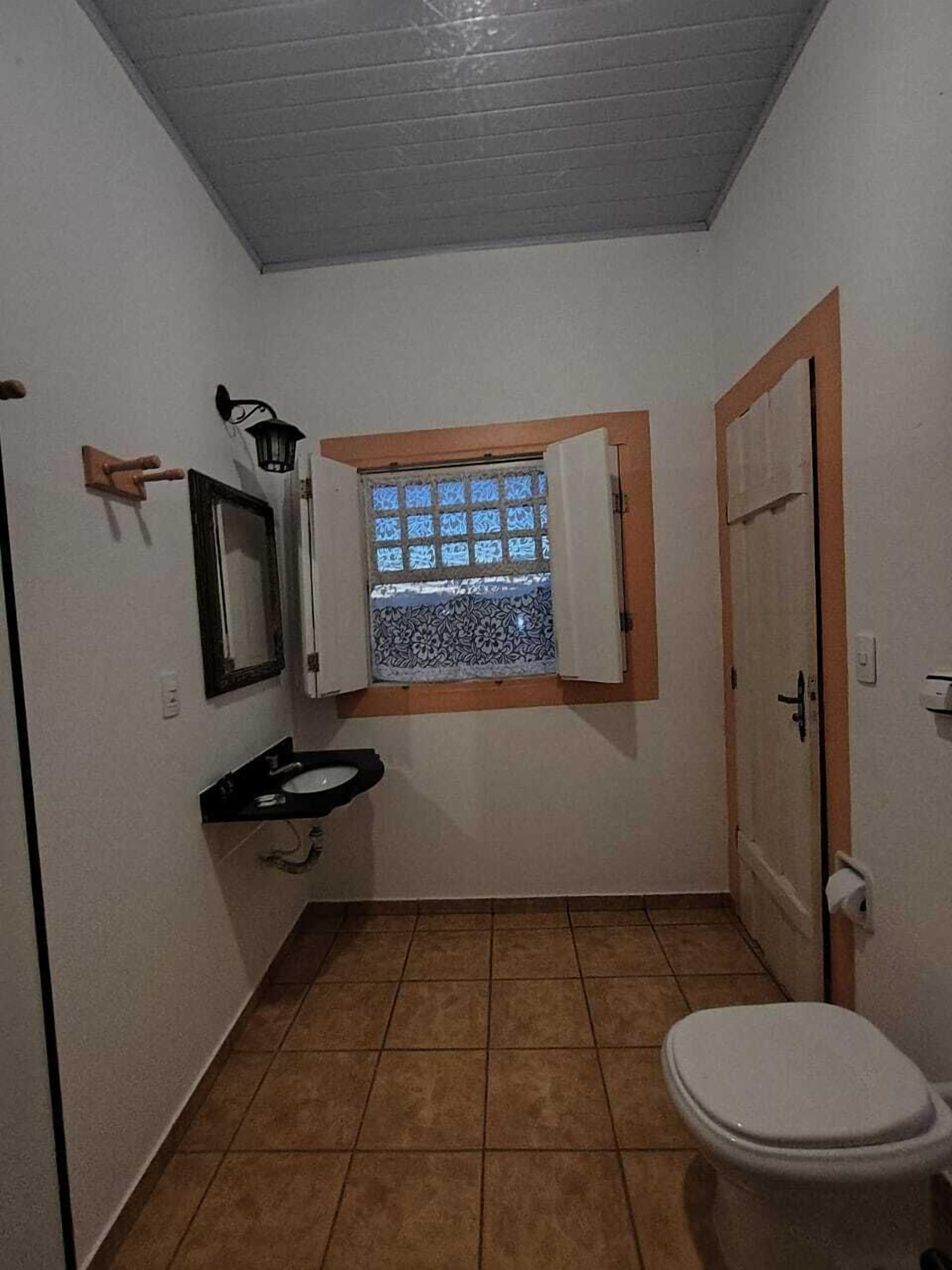 A small bathroom with a toilet, sink, and a window with a view.