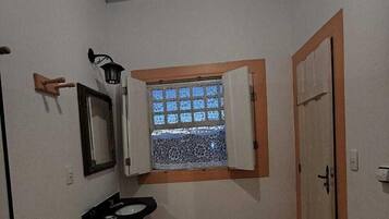 A small bathroom with a toilet, sink, and a window with a view.