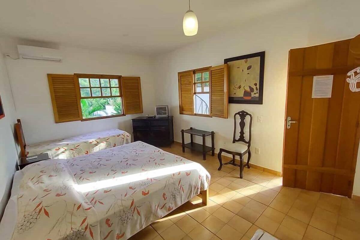 Un dormitorio con dos camas, un escritorio, una silla, un televisor y una puerta.