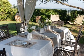 Un espace de restauration en plein air, avec des tables dressées pour le repas, entouré de chaises et offrant une vue sur le paysage.