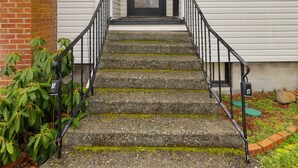 A two-story house with a front door, a satellite dish, and a staircase leading to the entrance.
