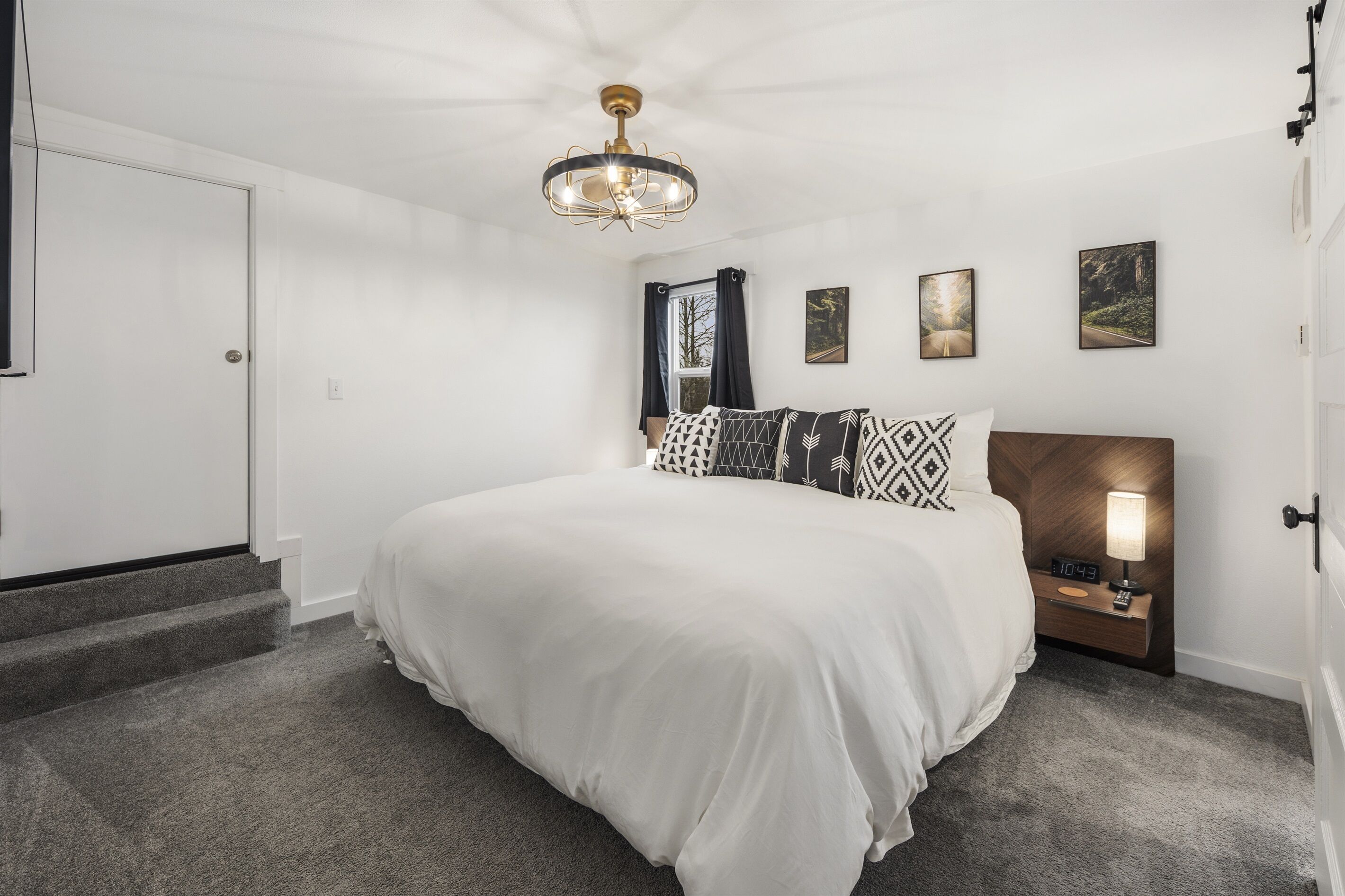 A bedroom with a large bed, a nightstand with a lamp, and a ceiling light fixture.