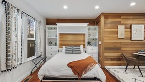 A bedroom with a bed, built-in shelving, a desk, and a radiator. - 1st floor in Duplex Chic 1BR Close to Mt. Rainier (Enumclaw)