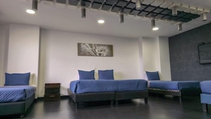 A hotel room with three beds, a ceiling with recessed lighting, and a wall-mounted artwork. - Hotel City Center Corferias (Bogotá)